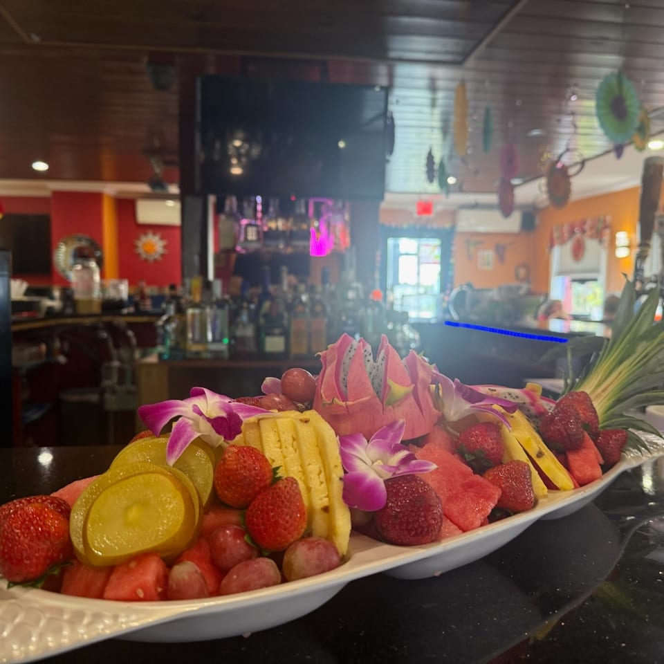 Fresh fruit platter with strawberries, pineapple, citrus, and orchids on the bar.