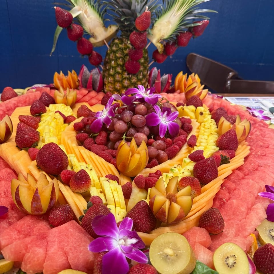Decorative fresh fruit platter with pineapple, berries, melon, and orchids.